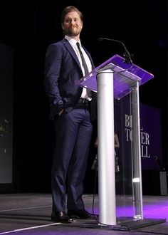 a man in a suit standing at a podium