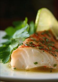 a close up of a plate of food with fish and lemon wedges on it