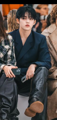 a man sitting on top of a white bench next to another person wearing black pants