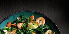 a green plate topped with shrimp, broccoli and carrots on top of a table