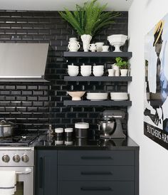 a black and white kitchen with pots, pans and bowls on the shelf above the stove