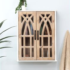 a wooden cabinet sitting next to a potted plant