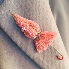 a pink butterfly brooch sitting on top of a white blanket