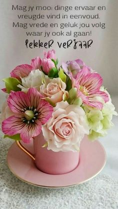 a pink coffee cup filled with flowers on top of a table