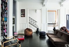 a living room filled with furniture and bookshelves next to a stair case full of books