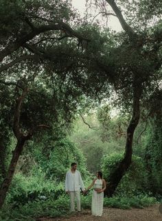 a man and woman holding hands in the woods