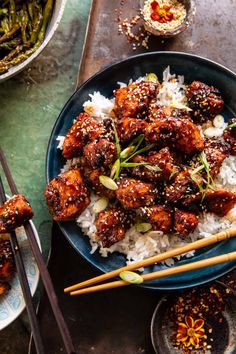 a plate with rice and meat on it next to chopsticks, asparagus and other foods