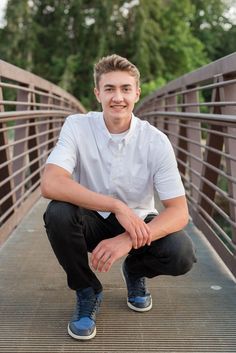 a young man is posing on a bridge