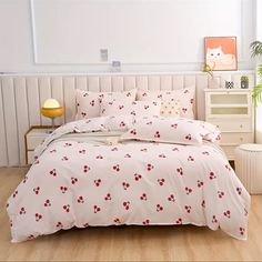 a bed with red flowers on it in a room next to a white headboard