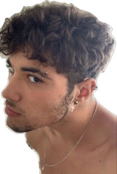 a young man with curly hair and piercings on his ear looking at the camera