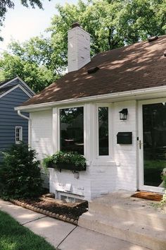 a small white house with a brick chimney