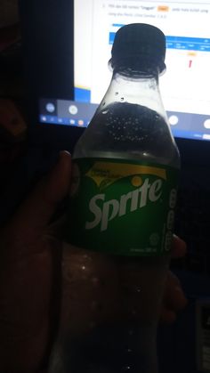 a bottle of sprite water in front of a laptop