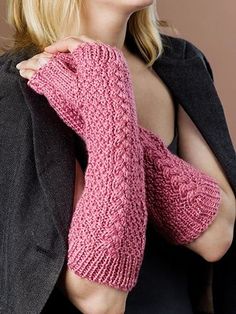 a woman wearing a pink knitted mitten and black jacket with her arms crossed