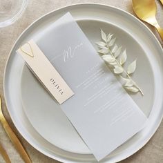 a table setting with place cards and gold cutlery