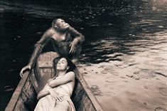 a woman in a boat with a monkey sitting on her head and another person laying down next to her