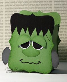 a close up of a paper cut out of a green monster with black hair and eyes