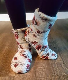 someone wearing slippers with flowers on them standing on a wooden floor in front of a wall