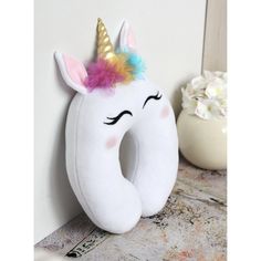 a stuffed unicorn is sitting next to a white wall