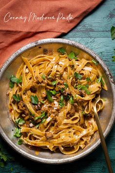 a bowl filled with pasta and meat on top of a wooden table next to an orange towel