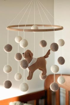 a toy dog is hanging from a mobile with balls on it's back end