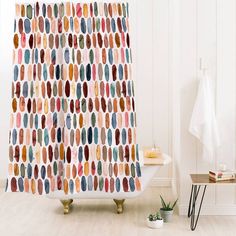 a bathroom with a shower curtain that has colorful circles on it and a plant in the corner