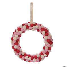 a red, white and pink beaded wreath ornament hanging from a string