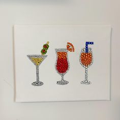 three different colored glasses are on a white paper with beaded trimming around the edges