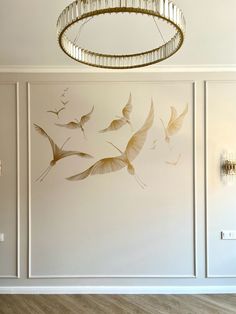 a chandelier hanging from the ceiling in front of a wall with birds painted on it