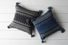 two blue and black pillows with tassels on them