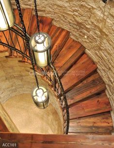 two light fixtures hanging from the side of a spiral stair case in a stone and wood building