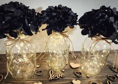 three vases filled with flowers sitting on top of a wooden table next to hearts