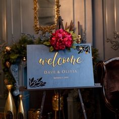 a welcome sign sitting on top of a wooden easel in front of a chair