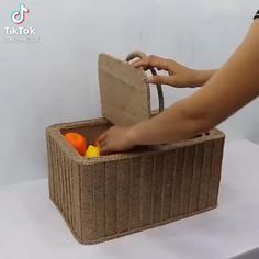 a person holding a brown basket filled with oranges and an object in the middle