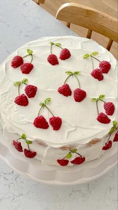 a cake with white frosting and raspberries on top sitting on a table