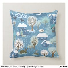 a blue pillow with houses and trees in the snow, on top of a white wall