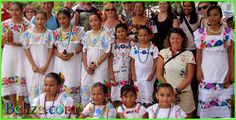 a group of women in white dresses posing for a photo with other people and children