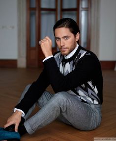 a man is sitting on the floor with his hand in his pocket and looking at the camera