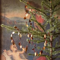 a small christmas tree with ornaments hanging from it's branches in front of a painting