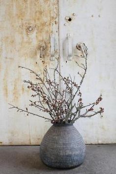 a vase filled with flowers sitting on top of a cement floor next to a wall