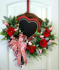 a heart shaped wreath with red flowers and greenery hangs on the front door,