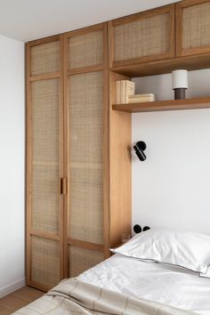 a bed sitting under a wooden shelf next to a white wall