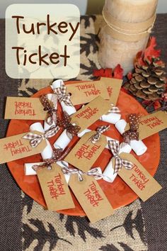 turkey ticket cards on an orange plate next to a candle and pineconi cones