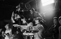 black and white photograph of people on set with cameraman in foreground looking at film