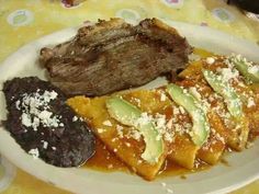 a white plate topped with meat and veggies on top of a yellow table cloth