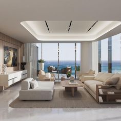 a living room filled with white furniture and large windows overlooking the ocean in front of it