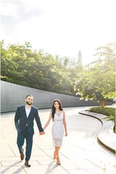 an engaged couple holding hands and walking through the park