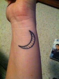 a small crescent tattoo on the wrist