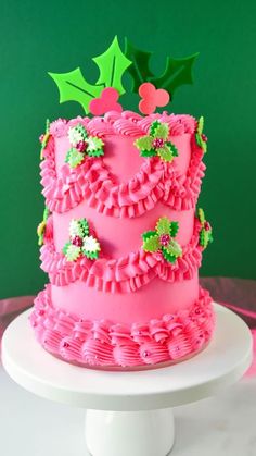 a pink cake with holly decorations on top