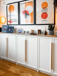 a white cabinet with pictures on it and other items sitting on top of the cabinets