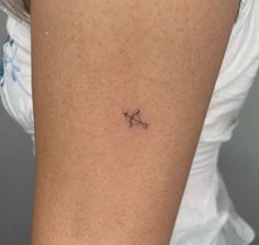 a small star tattoo on the back of a woman's thigh, it appears to be an astro sign